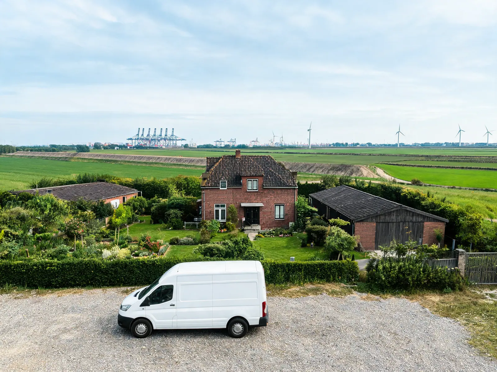 Woning in een polderdorp met havenkranen aan de horizon